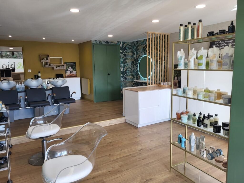 Intérieur du salon Coiff & Bio : bacs, murs vert sapin et ocre, étagères de produits
